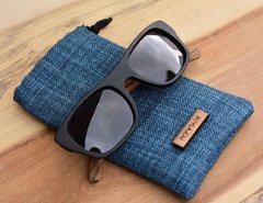 anteojos de madera (patillas) y acetato (frente) color negro de forma rectangular con lentes de sol polarizados modelo Córcega marca Nómade (vista de anteojo inclinado sobre funda)