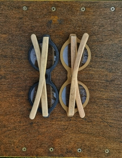 Dos anteojos de madera (patillas) y acetato (frente) color negro y oro de forma redondeada para colocar lentes de aumento modelo Sondrio marca Nómade ( vista posterior con anteojo cerrado)