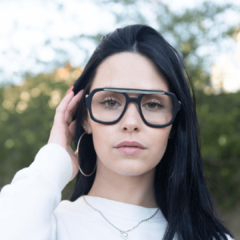 Mujer con anteojos de madera (patillas) y acetato (frente) color negro estilo aviador para colocar lentes de aumento modelo Barker marca Nómade