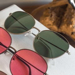 anteojos de sol de metal de forma redonda color plata con lentes polarizados color verde modelo los pioneros marca nomade con fondo de madera