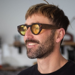 hombre con con anteojos de madera (patillas) y acetato (frente) simil carey con lentes color amarillo, forma redonda, estilo oversized modelo Skorpios TINT marca Nomade