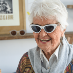 mujer con pelo corto usando anteojos de sol con patillas de madera y frente de acetato color blanco estilo pinup mddelo malibu marca nomade