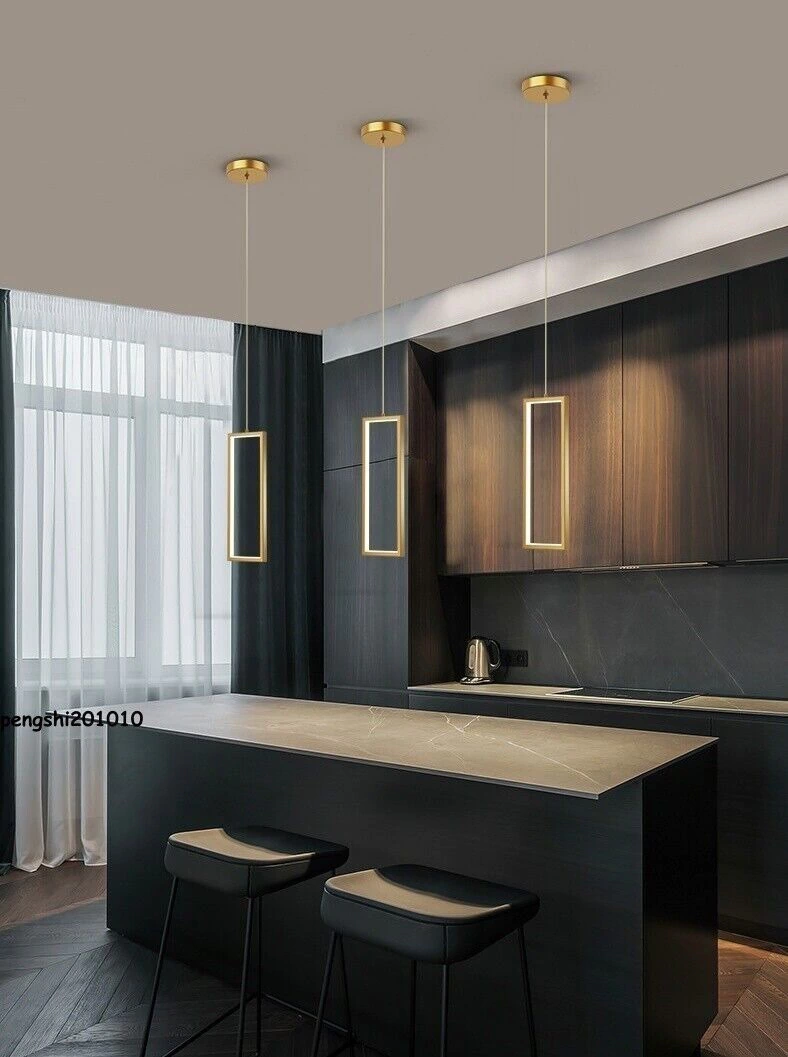 Iluminação pendente da Linha Mirror de LED Dourado em uma cozinha moderna, com bancadas escuras e janelas amplas.