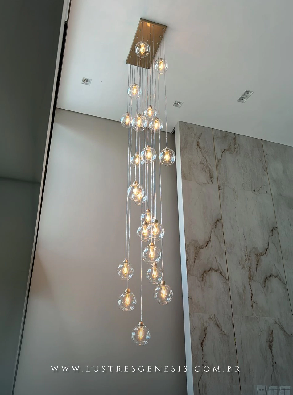 Lustre pendente com várias lâmpadas em vidro transparente, iluminando um ambiente moderno.
