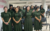 Grupo de mulheres vestindo uniformes verdes em um evento