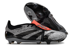 Chuteira campo Adidas Predator Elite Tongue com design em preto e cinza, destacando a parte superior em formato de pele de cobra e detalhes em laranja.