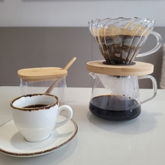 Passador de café na mesa posta com xícara e açucareiro.