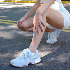 Zapatillas Vida Blanco en primer plano, modelo deportivo con detalles en malla, sobre una superficie de asfalto.