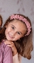 Nena con Vincha Eider rosa, de textura acanalada con moño y puntilla
