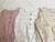 Variantes del body Boreales, de algodón con botones en pechera: en off white con lila, beige con verde, rosa con off white