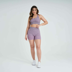 Modelo usando top feminino rosa mescla da linha Marcio May Sports, combinado com shorts de treino, em um fundo claro.