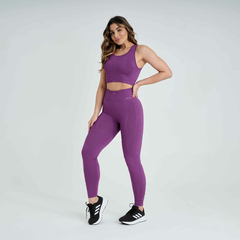 Calça legging feminina na cor uva, ideal para atividades físicas, combinada com um top de mesma cor e tênis preto.