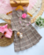 Look Kyra xadrez de saia plissada e colete com flor na internet