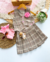 Look Kyra xadrez de saia plissada e colete com flor - comprar online