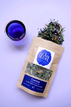 chá azul servido em xícara de vidro e pacote de chá azul de clitoria, capim cidreira e laranja.